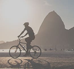 Homem andando de bicicleta na calçada da praia
