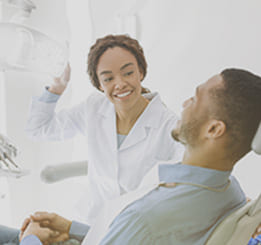Mulher dentista olhando para o paciente sentado na cadeira.