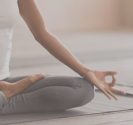 Mulher sentada com pernas cruzadas em posição de Yoga
