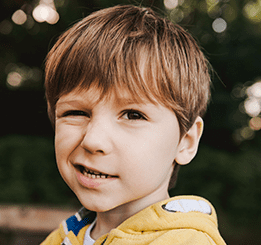 Imagem de menino sorrindo com um olho parcialmente fechado