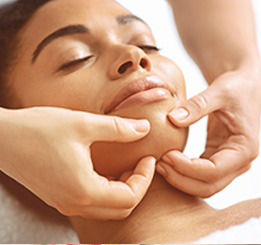 Mãos massageando rosto de mulher afrodescendente deitada