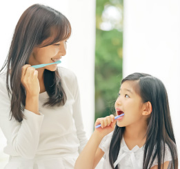 Mae e filha escovando os dentes